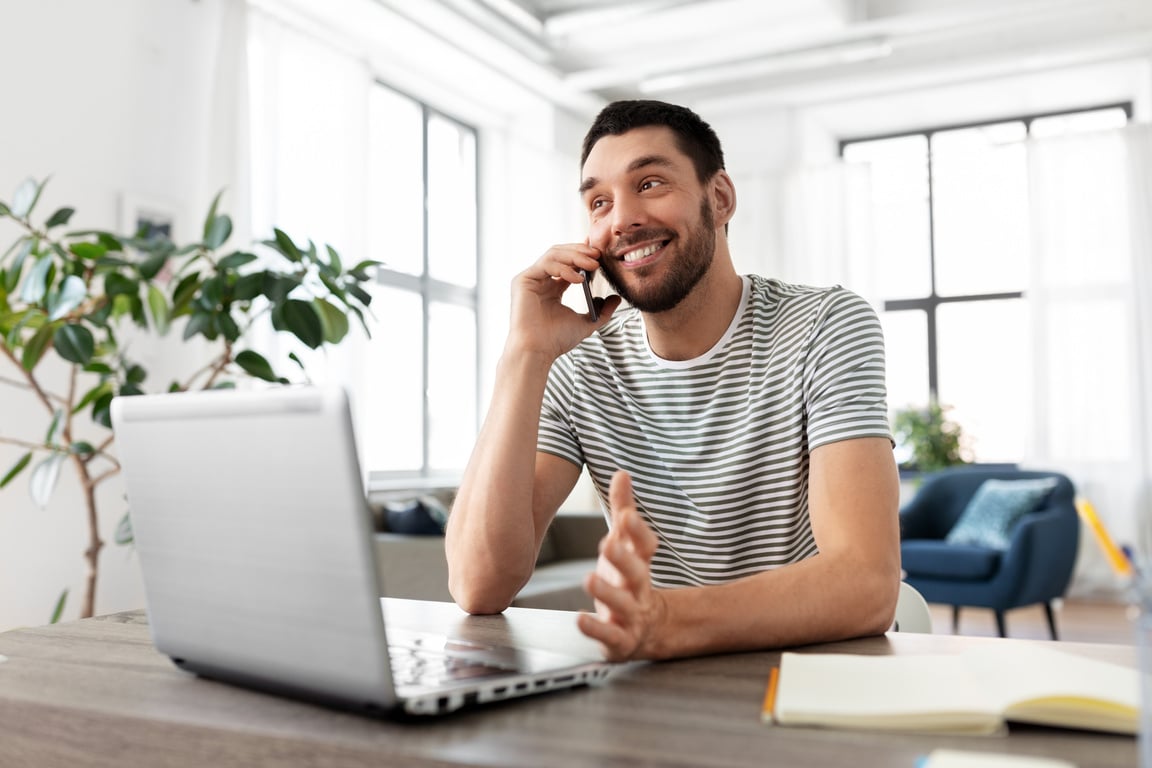 Man with Laptop Calling on Phone at Home Office